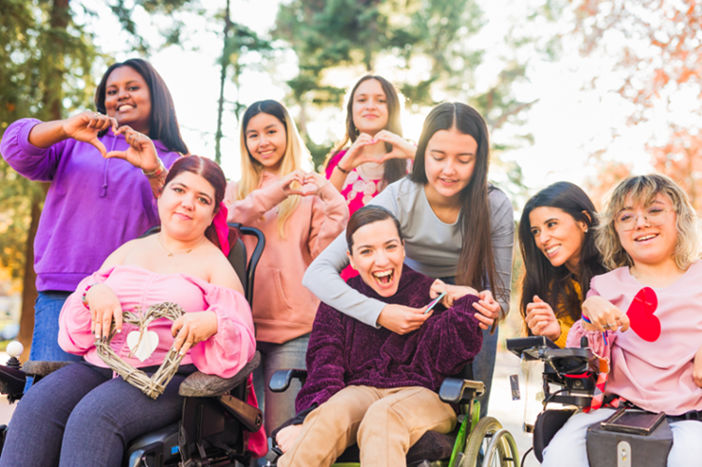 Social and Community Participation NDIS - International womens day Inspire Inclusion multiethnic group do love heart with hands. Wheelchair